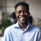 Confident smiling millennial african american businessman looking at camera in modern office, happy male professional company leader coach trainer posing alone, close up head shot business portrait